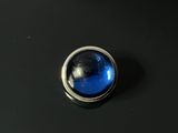 un gros plan d'un bouton bleu sur une surface noire