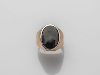 a gold and black stone ring on a white surface
