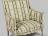 un fauteuil rembourré dont le dossier et les accoudoirs sont recouverts d'un tissu à rayures
