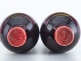 two wine bottles that have red caps on them