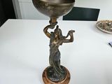a statue of a woman holding a bowl on top of a table