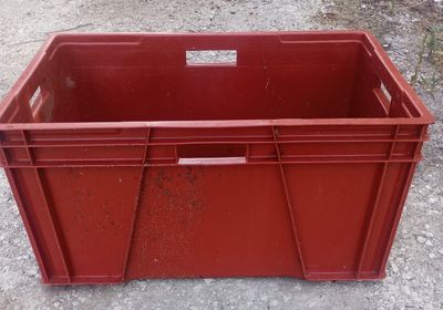a red plastic container sitting on top of a dirt ground