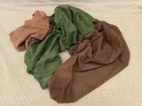 un tas de vêtements sur un lit recouvert d'une couverture blanche
