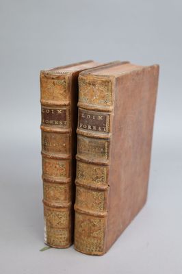 two old books sitting on top of each other on a white surface