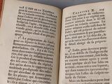 someone is holding a book open on a table with a hand on it