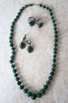 Ensemble collier et boucles d'oreilles orné de perles de verre vertes sur un fond en marbre