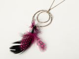 un gros plan sur un collier auquel est suspendue une plume