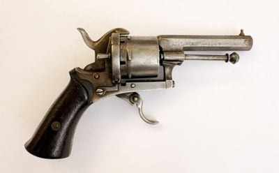 un vieux revolver avec une poignée en bois sur une surface blanche