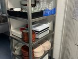 a metal shelf with plates and glasses on it in a kitchen