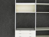 an overhead view of a white shelving unit with drawers and shelves