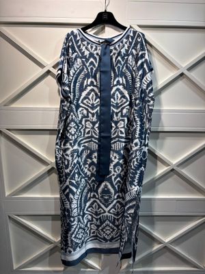 une robe bleue et blanche suspendue à un cintre devant un mur blanc