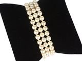 un gros plan d'un bracelet de perles blanches sur un nœud papillon en velours noir