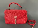 an image of a red handbag with a strap on a table