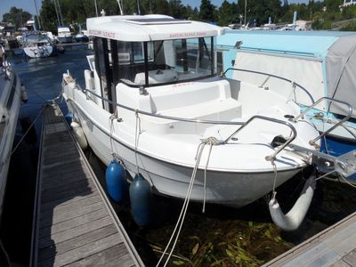 un bateau blanc amarré à un quai, avec d'autres bateaux en arrière-plan