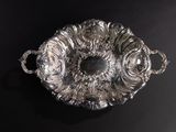 an antique silver plate with handles and handles on a black surface
