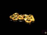 two yellow heart shaped diamonds on a black surface
