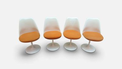 quatre chaises « Tulip » avec des coussins orange et des piètements blancs