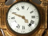a gold clock with roman numerals on the face