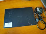 un ordinateur portable posé sur un bureau, avec un chargeur dessus