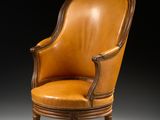 un fauteuil ancien en cuir, avec des pieds en bois et une assise rembourrée marron