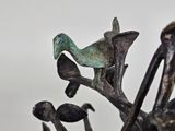 a statue of a bird sitting on a branch of a tree
