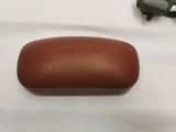 brown sunglasses case with a pair of sunglasses laying on a white surface