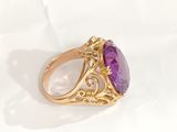 a close up of a gold ring with a purple stone