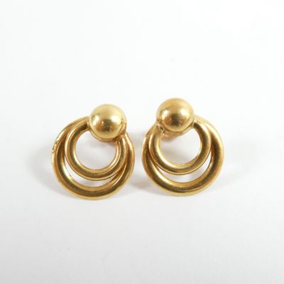 gros plan d'une paire de boucles d'oreilles en or sur une surface blanche