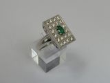a close up of a ring with a green stone surrounded by diamonds