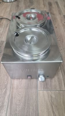 a silver stove with two pans on it on a wooden floor