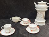 plusieurs tasses et soucoupes posées sur une table, avec un vase en arrière-plan