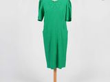 une robe verte posée sur un présentoir à mannequin, sur fond blanc