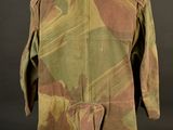 an old military jacket on a mannequin stand against a black background