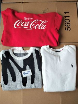 three t - shirts are sitting on a cardboard box with a coca cola logo on it