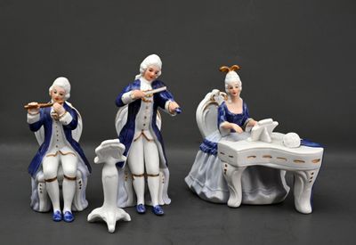 trois figurines représentant des personnes jouant d'un instrument de musique devant une table