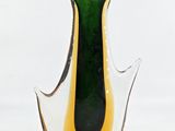 a green and yellow vase sitting on a white surface