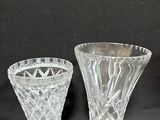 two clear glass vases sitting next to each other on a black surface