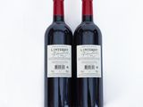 two bottles of red wine sitting next to each other on a white surface