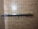 une étagère en métal dans un coin d'une salle de bains carrelée