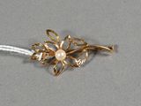 une photo d'une broche en forme de fleur en or ornée d'une perle