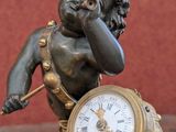 a statue of a boy holding a clock on a table