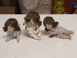 three figurines of children sitting on a table