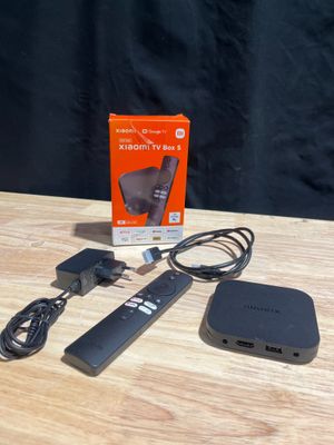 une image représentant une boîte posée sur une table, avec une télécommande et un chargeur à côté