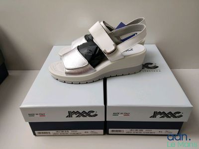 une paire de sandales blanches et noires posées sur des cartons, sur une table