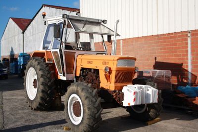 un gros tracteur orange garé devant un bâtiment