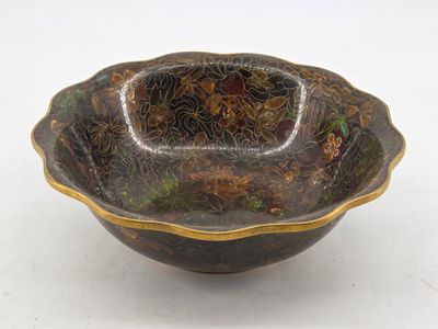 an image of a black and gold bowl sitting on top of a white table