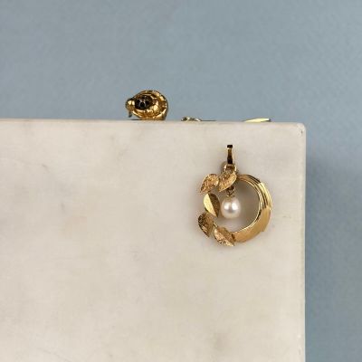 boucles d'oreilles en perles et en or posées sur un bloc de marbre blanc