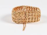 gros plan d'un bracelet en or sur une surface blanche