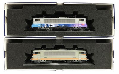 deux trains miniatures dans une boîte, posés sur une surface blanche
