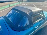 a blue car with a black top parked in a parking lot